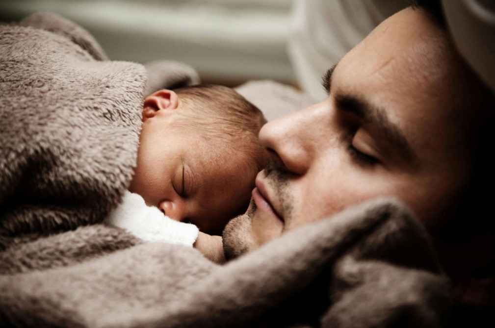 Man and his child lying in bad.